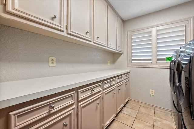 laundry area featuring cabinets, light tile patterned flooring, and washer and clothes dryer