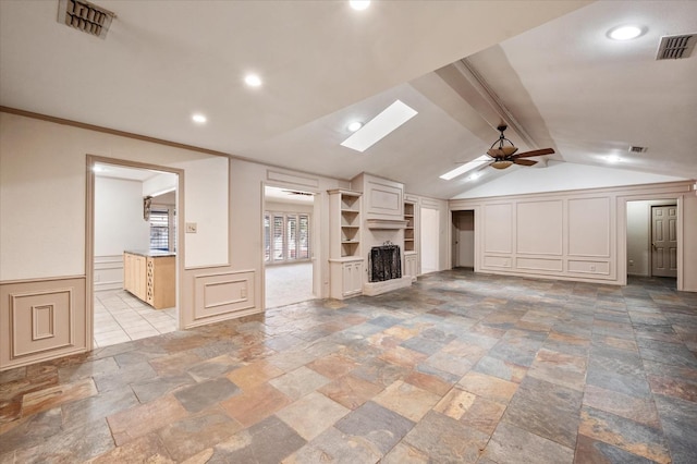 unfurnished living room with ornamental molding, lofted ceiling with skylight, and ceiling fan