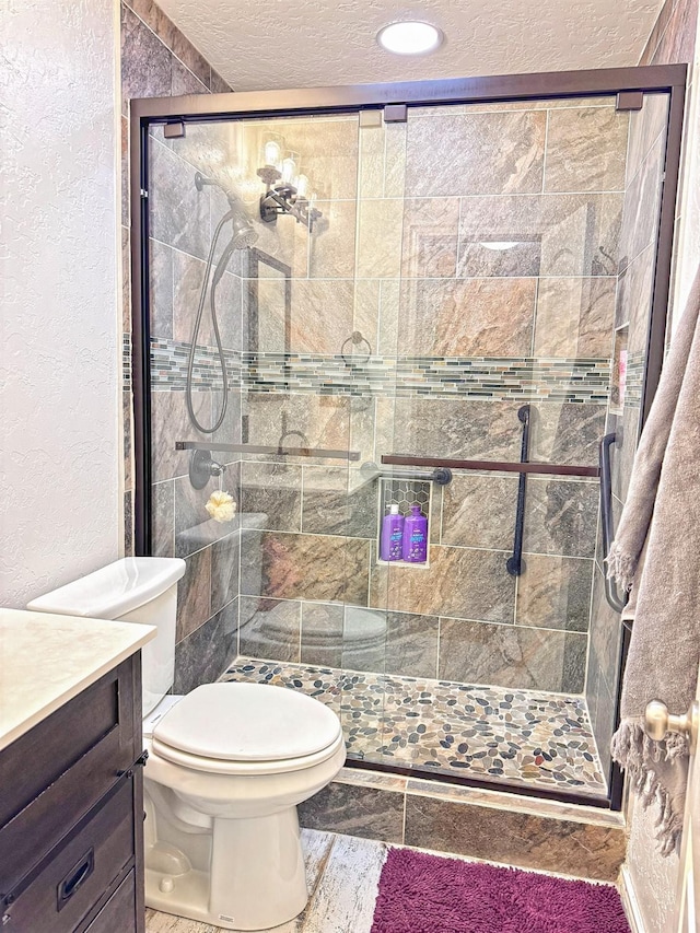 bathroom featuring vanity, toilet, an enclosed shower, and a textured ceiling