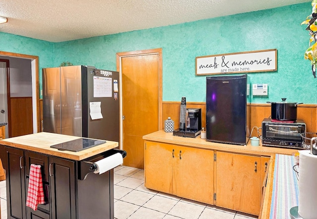 kitchen featuring light tile patterned floors, stainless steel fridge, and a textured ceiling