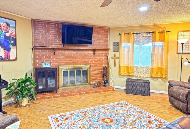 living room featuring hardwood / wood-style floors, a textured ceiling, a fireplace, and ceiling fan