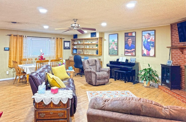 living room with ceiling fan, a textured ceiling, and light wood-type flooring