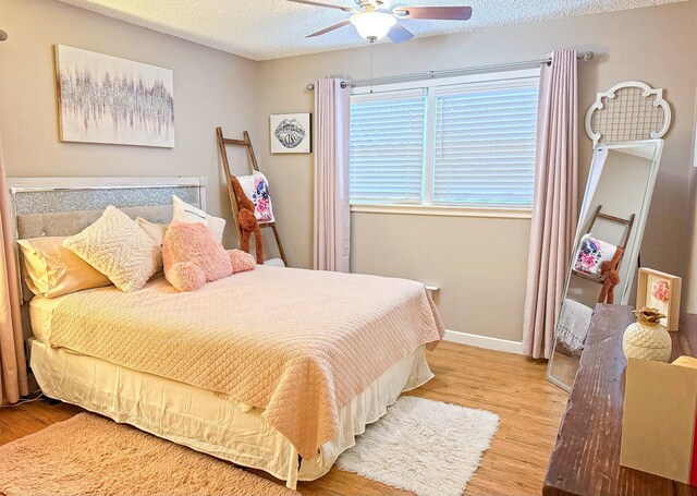 bedroom with ceiling fan, hardwood / wood-style flooring, and a textured ceiling