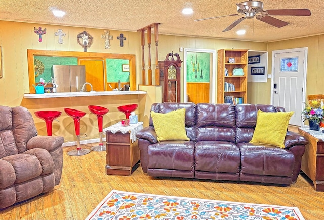 living room with hardwood / wood-style floors, a textured ceiling, and ceiling fan