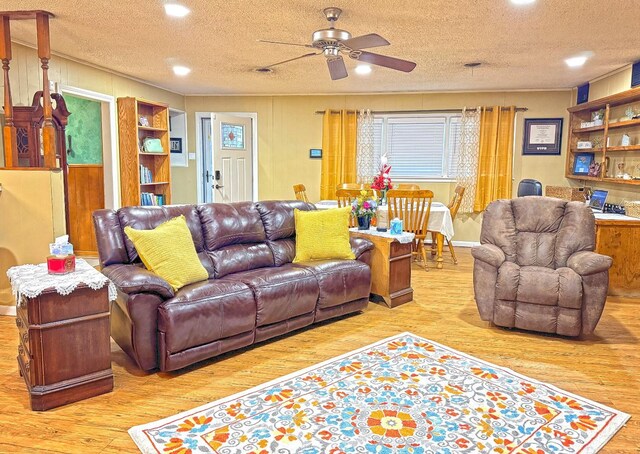 living room featuring ceiling fan, a textured ceiling, and light wood-type flooring