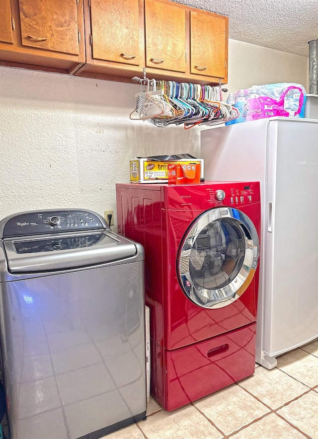 laundry area with cabinets, separate washer and dryer, and a textured ceiling