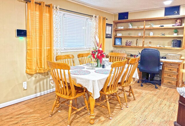 dining area with ornamental molding, light hardwood / wood-style floors, and a textured ceiling