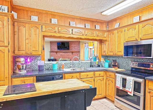 kitchen with butcher block counters, sink, light tile patterned floors, appliances with stainless steel finishes, and backsplash