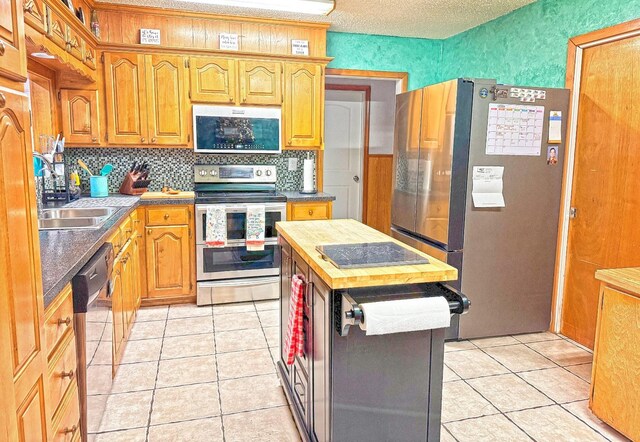 kitchen with light tile patterned flooring, appliances with stainless steel finishes, sink, and decorative backsplash