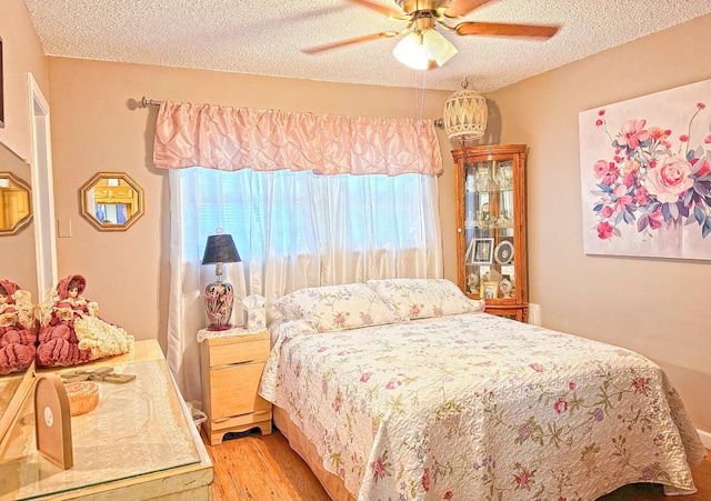 bedroom featuring ceiling fan, light hardwood / wood-style flooring, and a textured ceiling