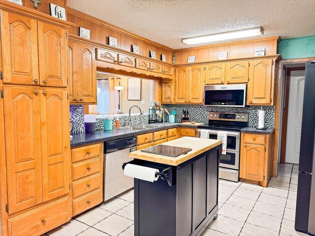 kitchen featuring sink, light tile patterned floors, stainless steel appliances, tasteful backsplash, and a kitchen island