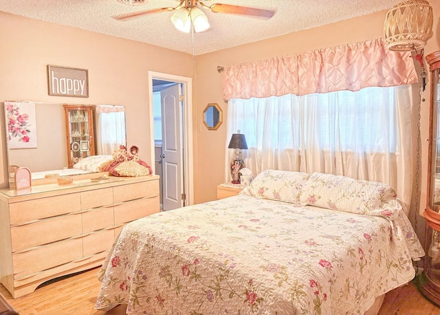 bedroom featuring ceiling fan, hardwood / wood-style flooring, and a textured ceiling