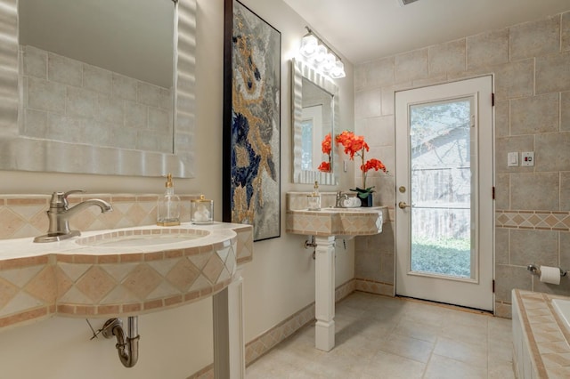 bathroom with tile patterned flooring, sink, a wealth of natural light, and tile walls