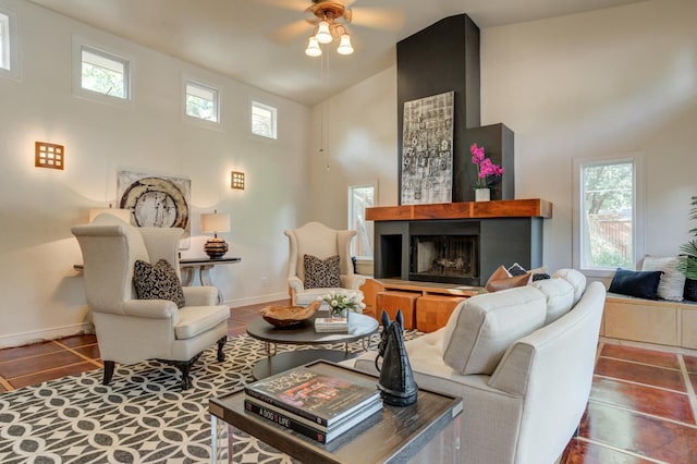 tiled living room with ceiling fan, a towering ceiling, a wealth of natural light, and a fireplace