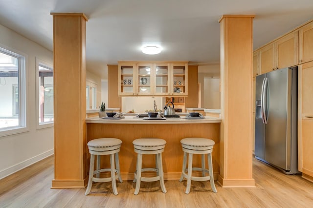 kitchen featuring stainless steel fridge, a kitchen breakfast bar, and light hardwood / wood-style floors