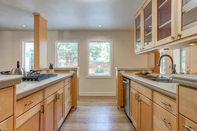 kitchen with appliances with stainless steel finishes, tile countertops, light brown cabinetry, sink, and light hardwood / wood-style floors