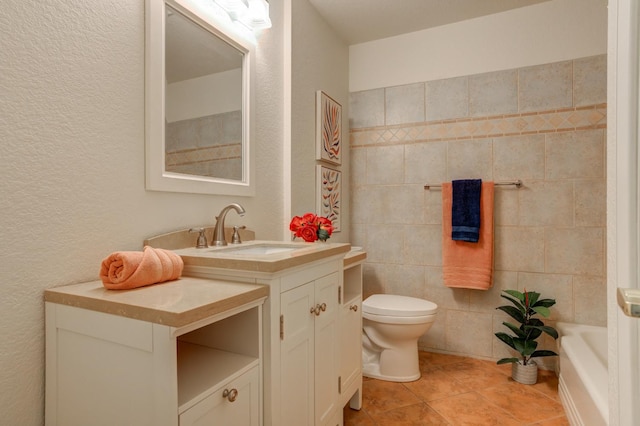 bathroom with tile walls, vanity, a tub to relax in, tile patterned floors, and toilet