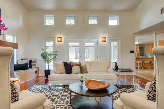 living room featuring french doors, tile patterned flooring, and a high ceiling