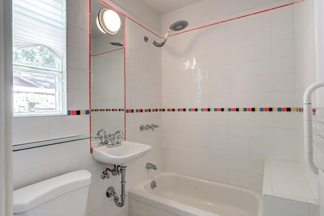 full bathroom featuring tiled shower / bath, toilet, sink, and tile walls