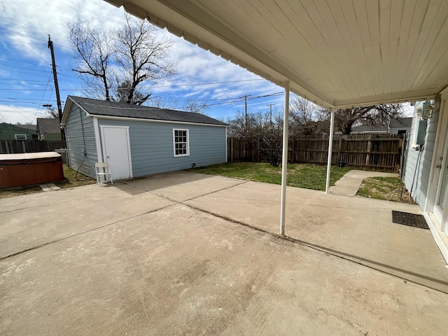 view of patio / terrace with a hot tub, a fenced backyard, and an outbuilding