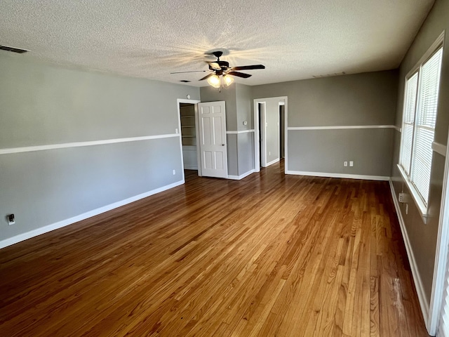 unfurnished bedroom with a textured ceiling, wood finished floors, visible vents, and baseboards