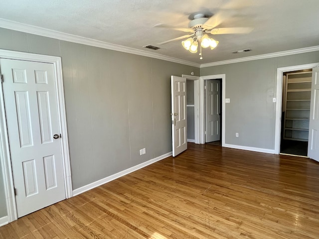 unfurnished bedroom with visible vents, wood finished floors, and ornamental molding