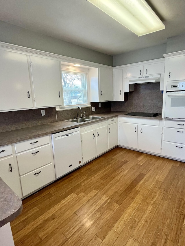 kitchen with light wood-style floors, white cabinets, a sink, white appliances, and under cabinet range hood