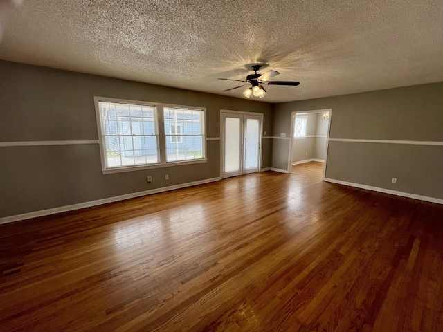 spare room with a ceiling fan, a textured ceiling, baseboards, and wood finished floors