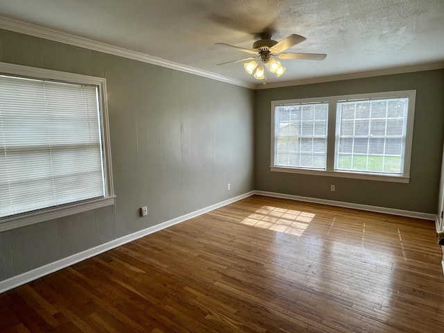 spare room with baseboards, a ceiling fan, wood-type flooring, a textured ceiling, and crown molding