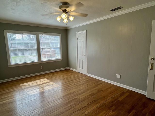 unfurnished room featuring baseboards, visible vents, a ceiling fan, ornamental molding, and wood finished floors