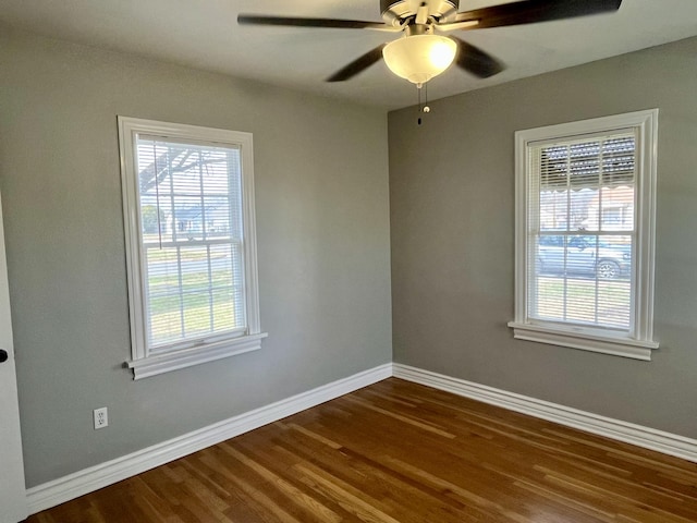 empty room with a ceiling fan, plenty of natural light, baseboards, and dark wood-type flooring