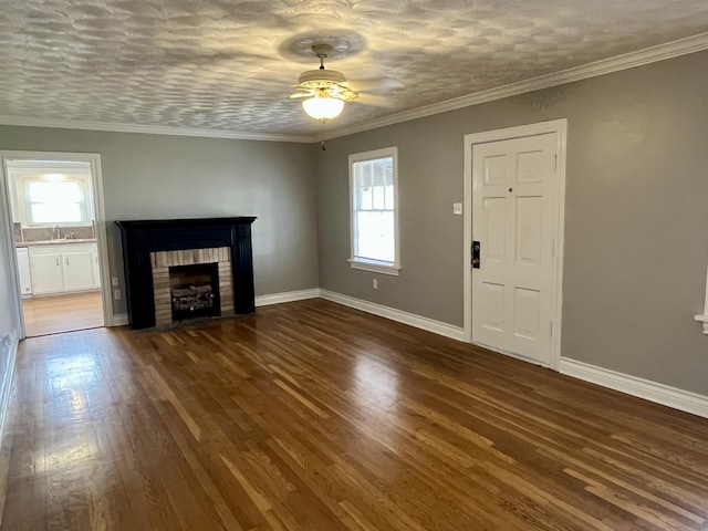 unfurnished living room featuring a fireplace, baseboards, dark wood finished floors, and crown molding