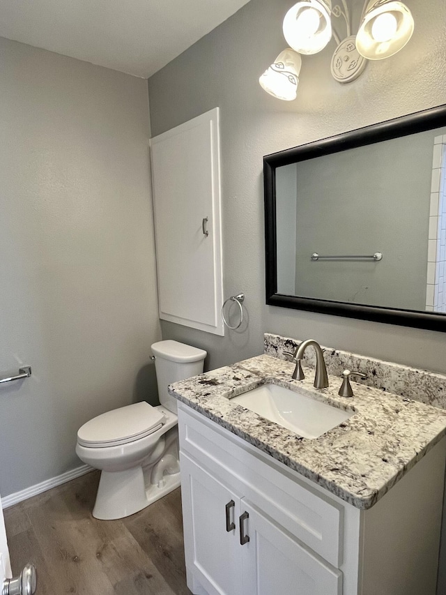 bathroom featuring vanity, wood finished floors, toilet, and baseboards