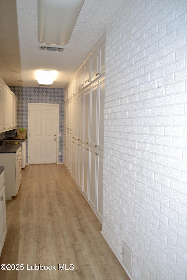200 Crescent Dr, Littlefield, TX 79339 - hallway featuring light wood-type flooring, brick wall, and visible vents