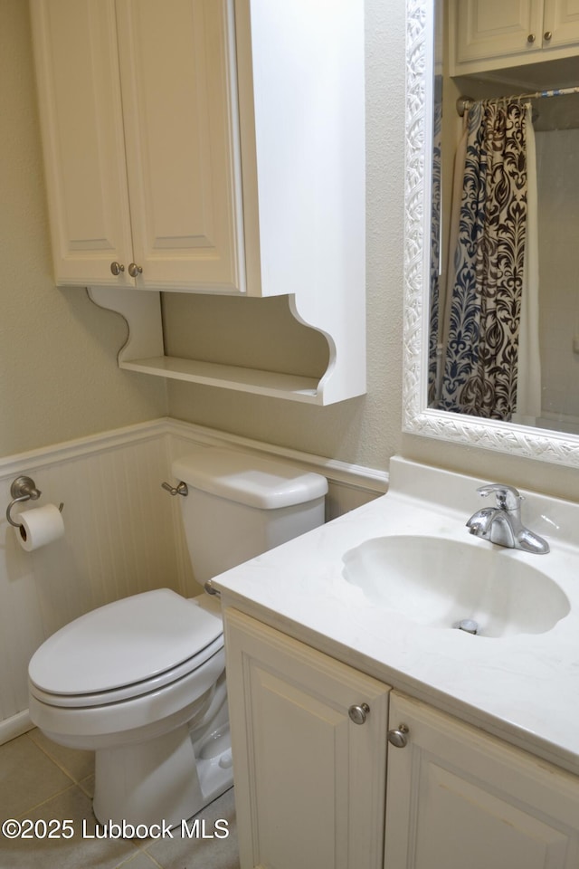 200 Crescent Dr, Littlefield, TX 79339 - full bathroom featuring tile patterned floors, vanity, toilet, and wainscoting