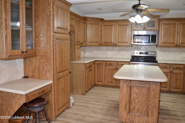 200 Crescent Dr, Littlefield, TX 79339 - kitchen with stainless steel appliances, tasteful backsplash, a ceiling fan, and brown cabinetry