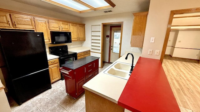 kitchen featuring a center island, sink, light hardwood / wood-style flooring, and black appliances