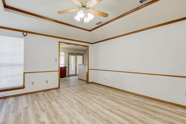 spare room featuring ceiling fan, light hardwood / wood-style flooring, ornamental molding, and a textured ceiling