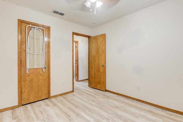 empty room with a textured ceiling, light hardwood / wood-style floors, and ceiling fan