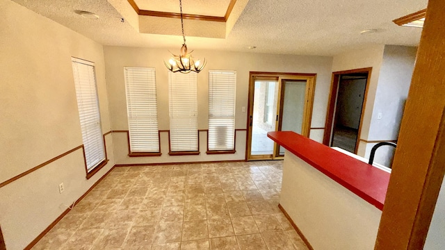 hall with a notable chandelier, a tray ceiling, and a textured ceiling