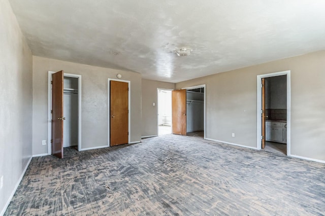 unfurnished bedroom featuring multiple closets and ensuite bathroom