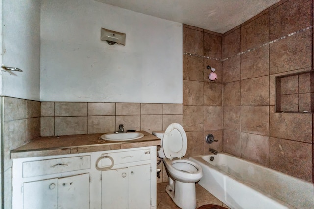 full bathroom featuring vanity, tiled shower / bath, tile walls, and toilet