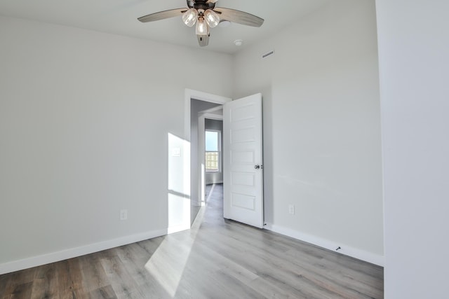 spare room featuring wood finished floors, ceiling fan, and baseboards