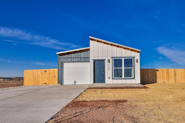 garage featuring fence and concrete driveway