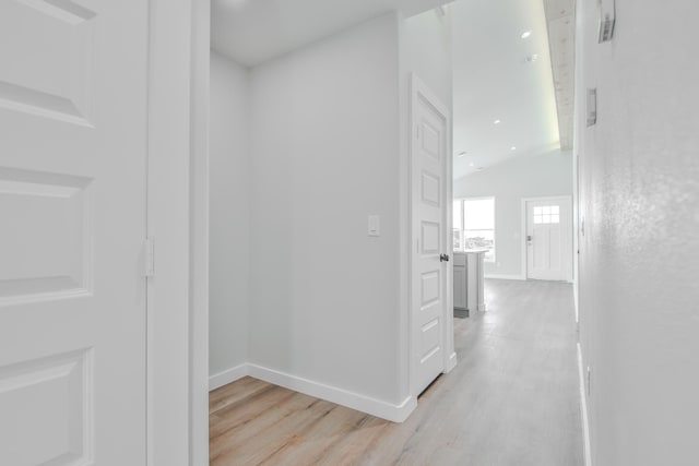 hall featuring baseboards, light wood-type flooring, lofted ceiling, and recessed lighting