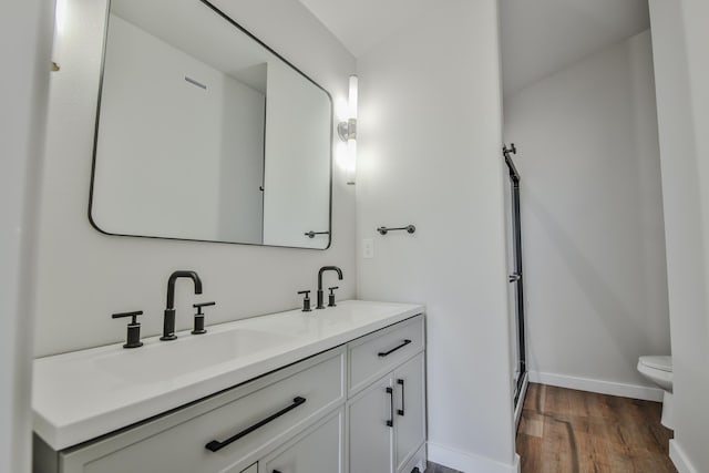 full bathroom featuring baseboards, wood finished floors, toilet, and a sink