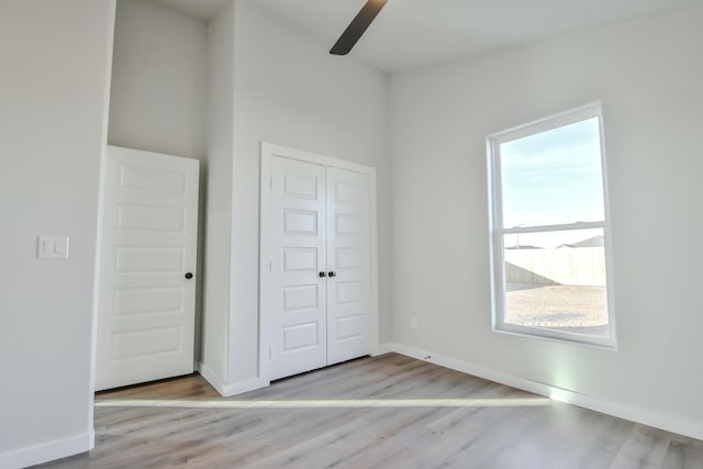 unfurnished bedroom with baseboards, wood finished floors, a ceiling fan, and a closet