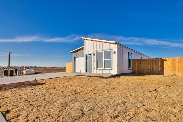 exterior space featuring an outbuilding, driveway, board and batten siding, and fence