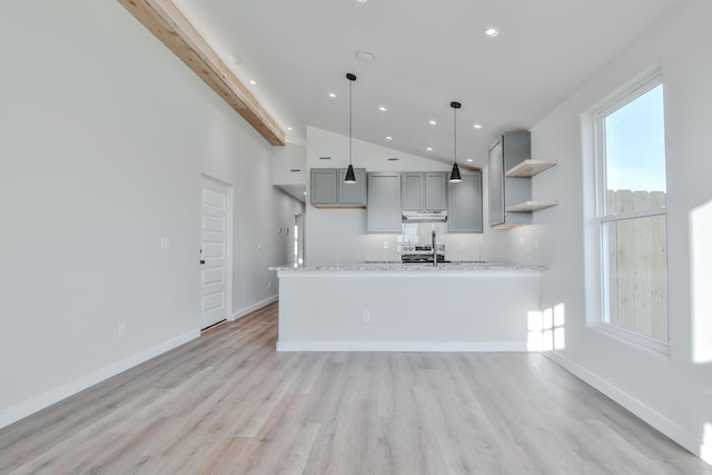 kitchen with gray cabinetry, light wood-type flooring, vaulted ceiling with beams, and under cabinet range hood