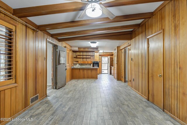 3413 42nd St, Lubbock, TX 79413 - kitchen featuring brown cabinetry, beamed ceiling, wooden walls, a peninsula, and light wood finished floors